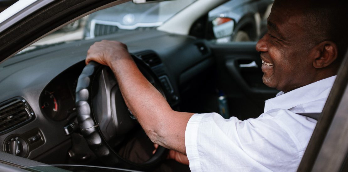 Man smiling while driving his car knowing the savings he will receive from his insurance company for being a safe driver.